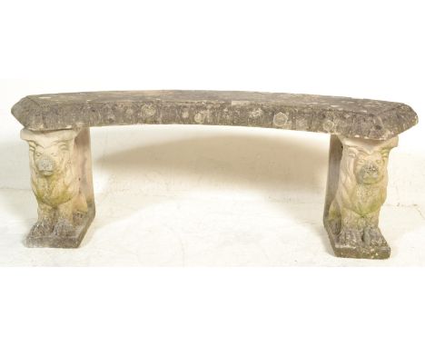 A reconstituted stone garden bench of arched form being raised on armorial lion plinths. Each lion&nbsp; supporting the arche