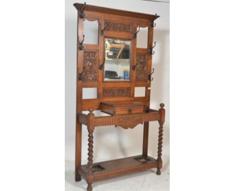 A late Victorian solid oak hall stand with central bevelled mirror flanked by carved panels, metal coat hooks, single glove c