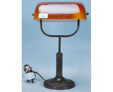 A vintage 20th Century brass bankers lamp having an orange shade with column stem raised on a circular base.&nbsp;