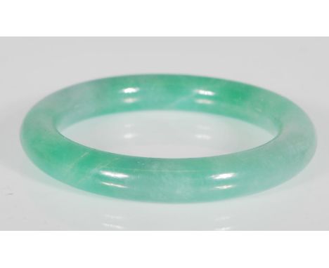 A Chinese green jade bangle of typical round form. Interior diameter 5.8cm. Weighs 65.1g.