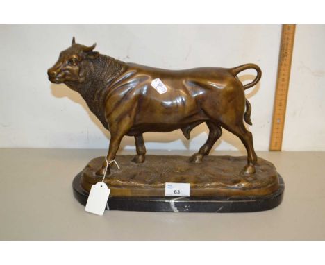 A contemporary bronzed metal model of a bull set on a polished marble base