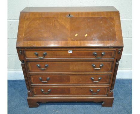 A 20TH CENTURY MAHOGANY BUREAU, the fall front door enclosing a fitted interior, over four drawers, flanked by Corinthian sty