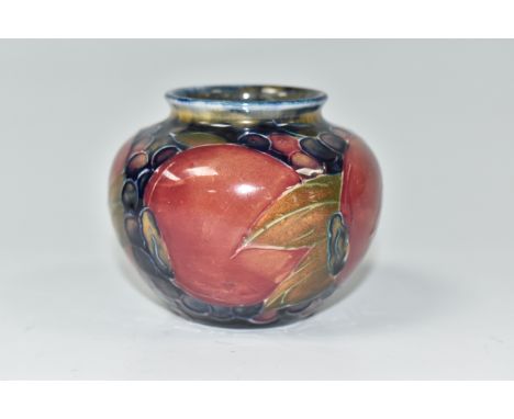 A MOORCROFT POTTERY POMEGRANATES VASE, of squat form, tube-lined with pomegranates and other fruit on a navy blue ground, pai
