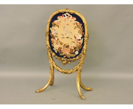 A gilt firescreen, centred with a needlework of a crest, 100cm high