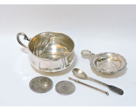 A German silver cup, a silver tea strainer, Irish silver egg spoon, a silver swizzle stick, a silver trade dollar 1911, and a