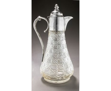 An Edwardian silver mounted cut glass claret jug, the pear shaped cut glass body with plain collared silver mount double scro