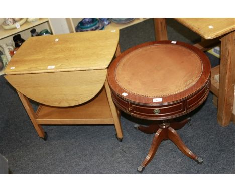 A reproduction small mahogany drum table, and an Ercol-type light oak tea trolley