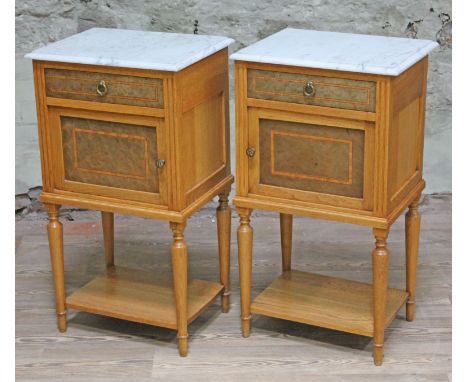 A pair of continental light oak bedside cabinets having carrara marble tops, with tulip and ebony crossbanded bird's eye mapl