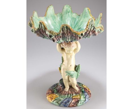 A 19TH CENTURY CONTINENTAL MAJOLICA COMPORT, CIRCA 1870S designed as a putti amongst bullrushes holding aloft a shell, to a n