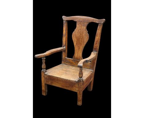 AN 18TH CENTURY OAK CHILD'S COMMODE CHAIR with yoked crest rail and hinged seat. Height of back 56cm