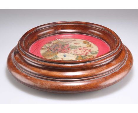 A 19TH CENTURY MAHOGANY AND NEEDLEWORK BOTTLE COASTER circular, with brass castors. 26.5cm diameterNeedlework with some very 