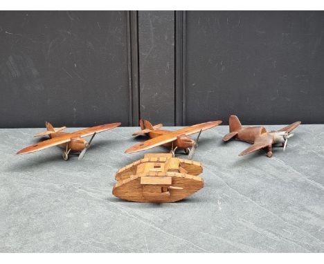 A vintage carved oak WWI British MK1 male tank, with lidded top, approximately 20cm long; together with three vintage carved 