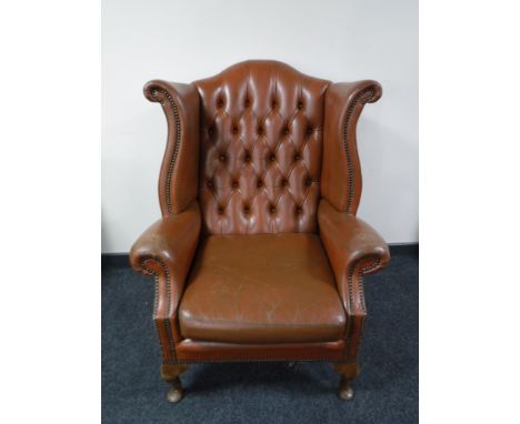 A brown button leather Chesterfield wing back armchair 