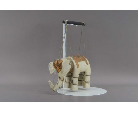 A mid 20th century Indian carved wooden Elephant puppet, articulated trunk and legs, the head and back with coloured glass an