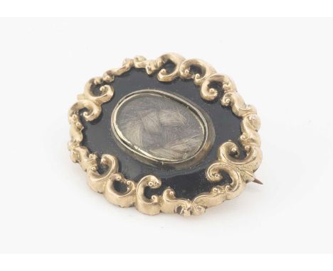 A dated Victorian mourning brooch, oval in shape with a central panel of plaited hair, with in a border of black enamel, scro