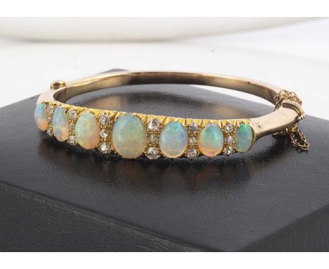 An early 20th Century opal and diamond hinge bangle, seven graduated oval cabochon opals alternately set with sets of three o