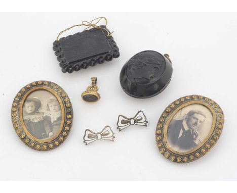 A Whitby Abbey jet miniature plaque, together with an oval jet locket, a pair of buckle style miniature photograph frames, a 