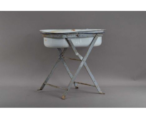 An early 20th century enamel bidet and cover on a metal stand, the finish work and stained, later with pierced holes, to be p