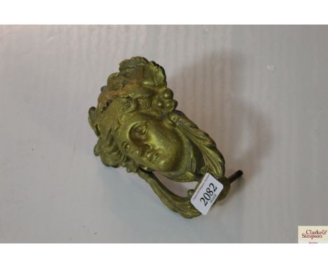 An antique gilded metal door knocker with mask decoration