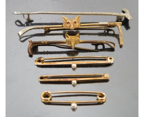 A yellow metal stock pin, formed as a hunting crop with foxes mask and having ruby eyes, together with two other stock pins, 