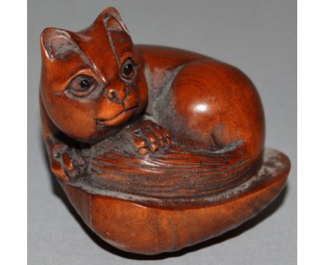A CARVED WOOD NETSUKE, a cat on a clam. Signed. 