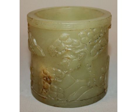 A CHINESE CELADON-GREEN JADE-LIKE BRUSH POT, the sides decorated in relief with a continuous river landscape setting, 2.9in d