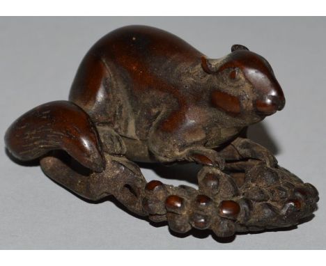 A CARVED WOOD NETSUKE, a rat on fruit. 