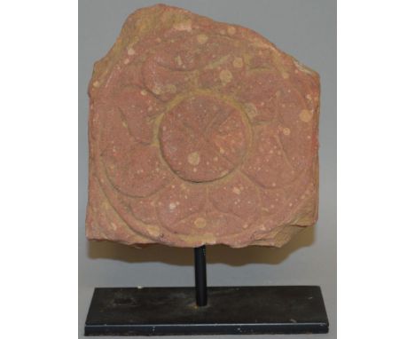 AN INDIAN CARVED TERRACOTTA FRAGMENTARY TILE of stylised flower head design. 5ins wide. 