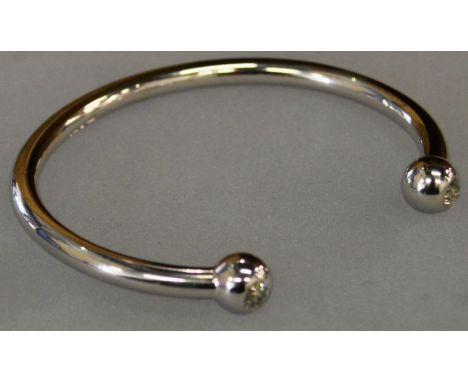 A HEAVY PLATINUM BANGLE the ends inset with a diamond. 