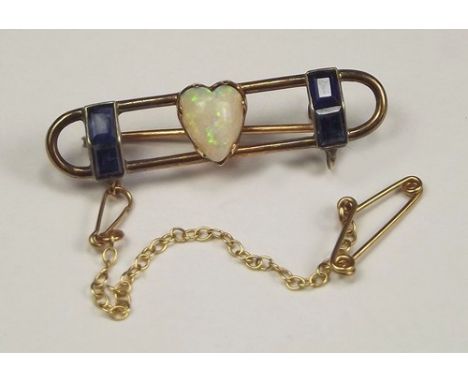 OPAL BROOCH.
A yellow metal brooch, set a heart shaped opal & flanked by pairs of baguette cut sapphires. Length 3.5cm.