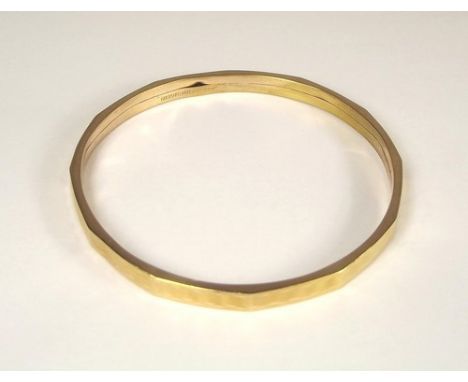 SLAVE BANGLE.
An engine turned slave bangle of 9ct. gold shell.