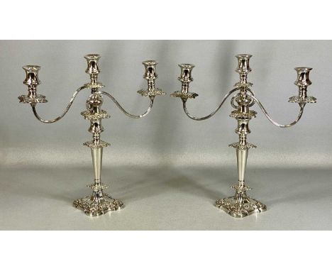 PAIR OF ORNATE PLATED THREE-BRANCH CANDELABRA, with floral and scroll embossed decoration, 42cms (h)Provenance: private colle