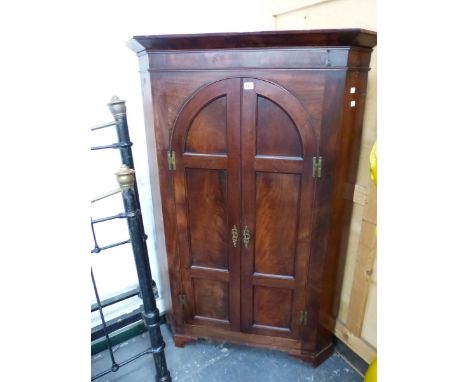 A GEORGE III MAHOGANY FLOOR STANDING CORNER CABINET WITH ARCH TOP PAIR OF PANEL DOORS. 