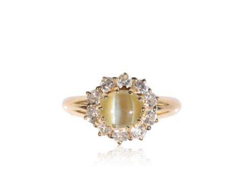 CHRYSOBERYL CATS EYE AND DIAMOND RING, the oval chrysoberyl cats eye, surrounded by a border of ten diamonds, on an unmarked 