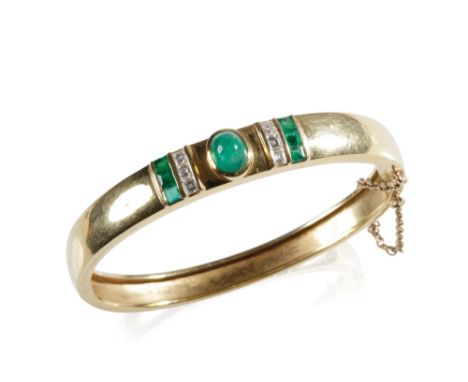 18K YELLOW GOLD EMERALD AND DIAMOND BANGLE, the centre set with an oval-cut cabochon emerald, flanked either side by a row of