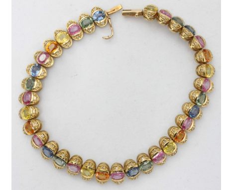 A 9ct yellow gold and fancy sapphire line bracelet, formed as twenty-four elliptical cells each centrally set with gemstones 
