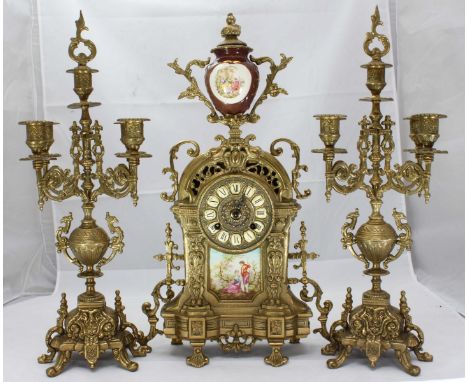 A 19th Century brass clock garniture in the Rococo style, the clock case with central panel depicting a couple in classical d