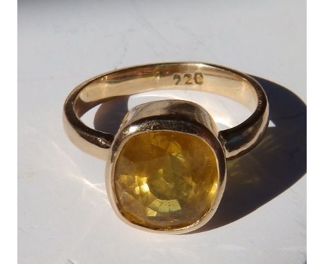 An oval cut yellow sapphire solitaire ring in yellow metal – the sapphire weighing approximately 3.8 carats – '22c'.  Finger 
