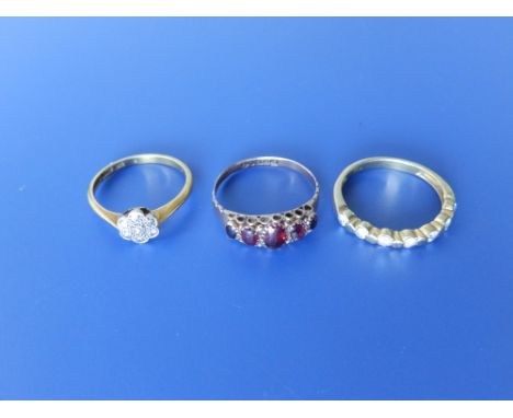 A small diamond cluster ring, a diamond half eternity style yellow metal '750' ring and a 9ct garnet ring. (3)