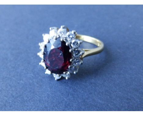 A modern oval diamond cluster with red stone (?) to centre – '18ct'. Finger size M.