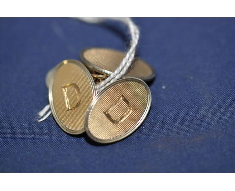 A pair of 9ct. yellow gold cufflinks, each oval plaque with engine turned decoration, and one of each cufflink engraved initi