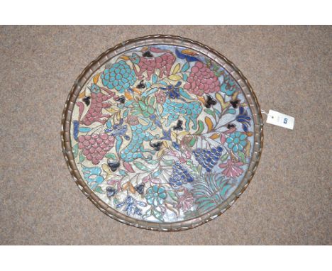 A circular copper and enamel tray depicting cats amongst foliage and grapes.