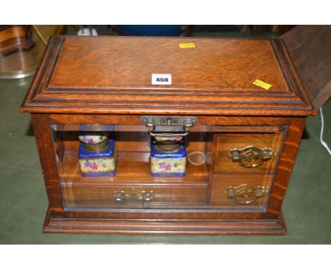 An early 20th Century oak desk top stationary cabinet, the glazed bevelled fall-flap opening to reveal letter tray, drawers, 