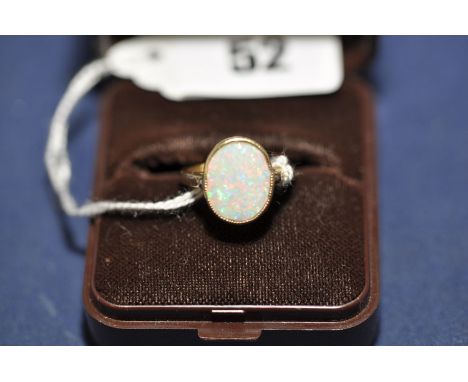 An opal ring, the oval opal plaque in millegrain mount, on 9ct. yellow gold shank, ring size H.