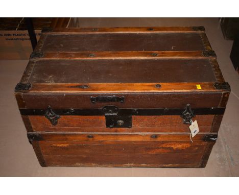 A wooden trunk with metal bindings containing an old teddy bear and various dolls house furniture, etc.