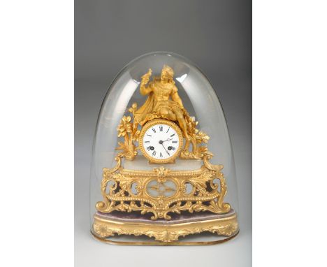 French Gilt Figure Mantel clock, a lady holding a bird over clock on wooden stand with glass dome