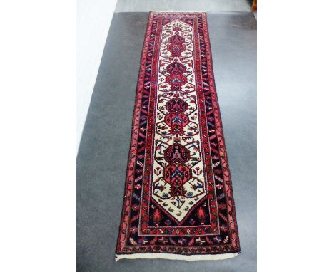 Eastern runner, the red field with foliate medallions and flowerhead borders, 300 x 84cm 