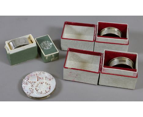 A silver and mother of pearl powder compact and three boxed silver serviette rings.