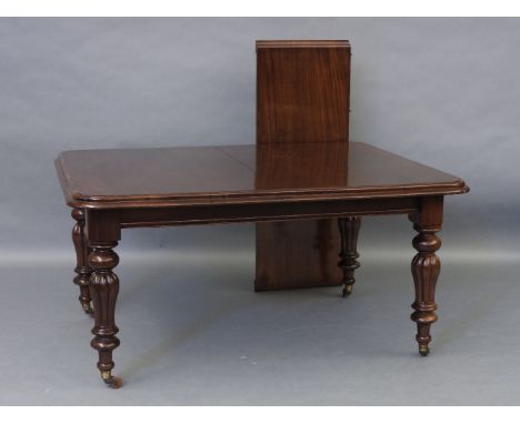 A Victorian mahogany wind out extending dining table, with ring turned and reeded legs, terminating in brass feet and ceramic