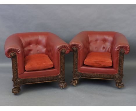 A pair of early 20th century red leatherette upholstered club armchairs, with button backs and ornately carved frames, each a